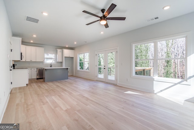 unfurnished living room featuring french doors, ceiling fan, and light hardwood / wood-style flooring