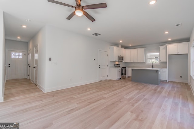 kitchen with white cabinets, a center island, ceiling fan, light hardwood / wood-style floors, and stainless steel appliances