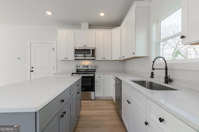 kitchen featuring sink, white cabinetry, gray cabinetry, stainless steel appliances, and light stone counters