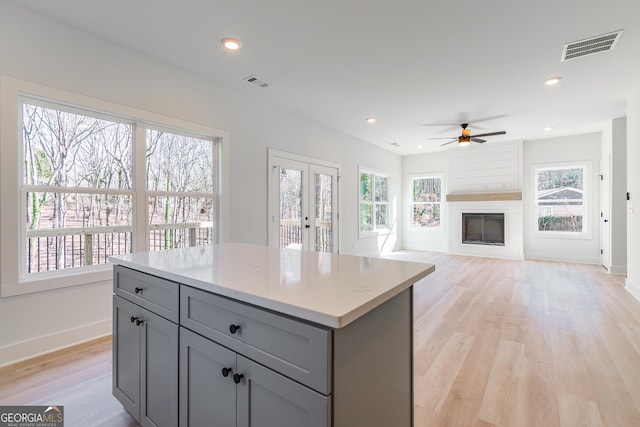 kitchen with a large fireplace, a healthy amount of sunlight, a kitchen island, and gray cabinetry