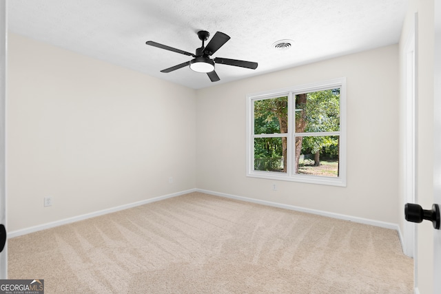 spare room with light carpet, ceiling fan, and a textured ceiling