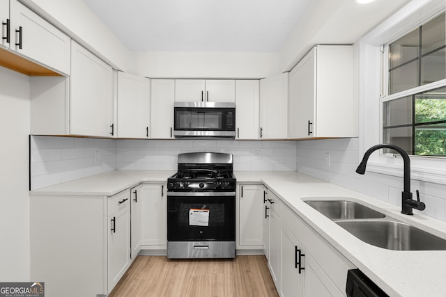 kitchen with white cabinets, appliances with stainless steel finishes, light wood-type flooring, and sink