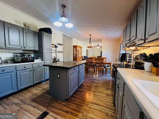 kitchen featuring an inviting chandelier, hanging light fixtures, dark wood-type flooring, and stainless steel electric range