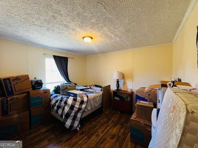 bedroom featuring dark hardwood / wood-style flooring, ornamental molding, and a textured ceiling