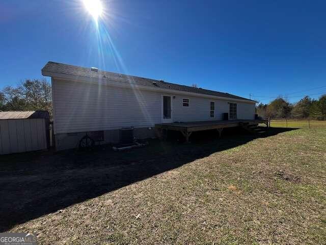 rear view of house featuring a deck and a yard