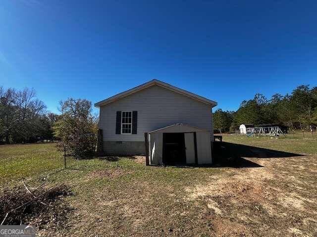 back of property with a lawn and a storage unit