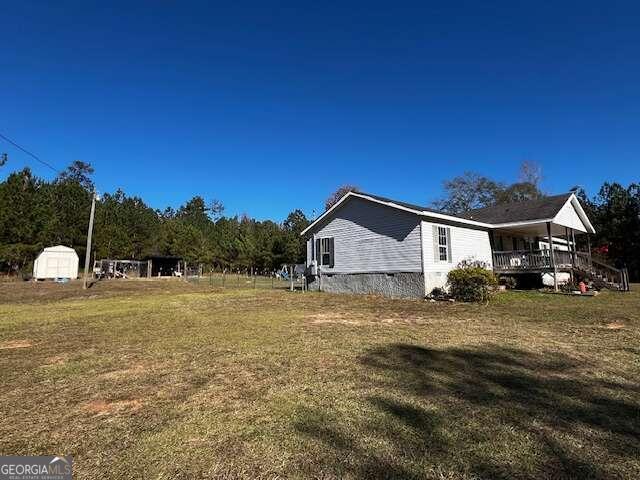 view of property exterior with a lawn, covered porch, and a storage shed