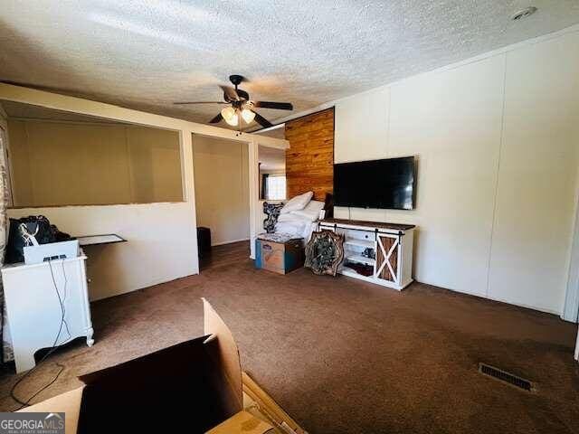 living room with dark colored carpet, a textured ceiling, ceiling fan, and wooden walls