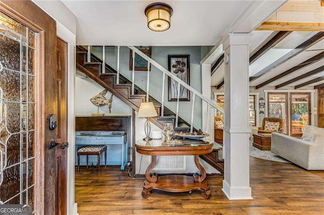 stairway with ornate columns, beamed ceiling, and hardwood / wood-style flooring