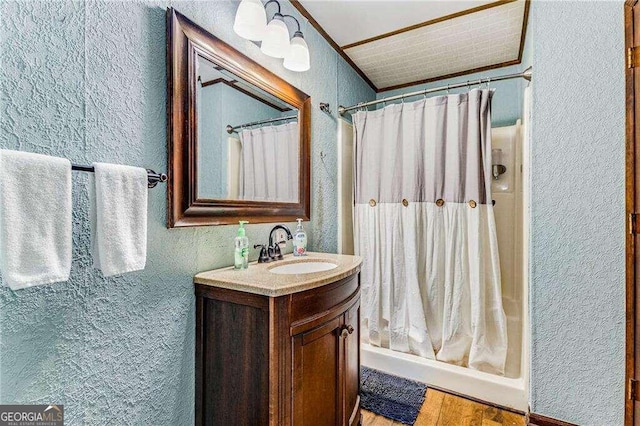 bathroom with a shower with shower curtain, wood-type flooring, vanity, and crown molding