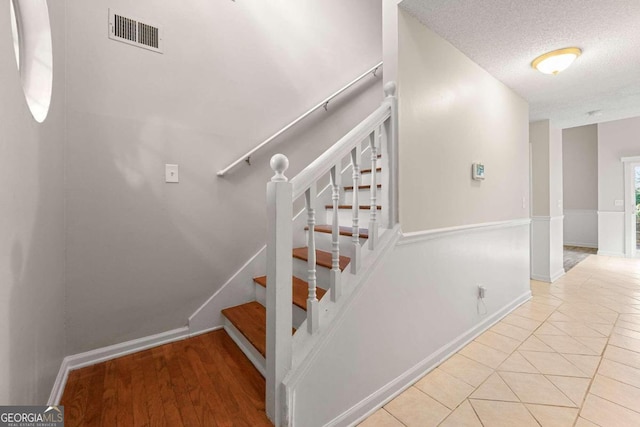 stairway featuring hardwood / wood-style flooring and a textured ceiling