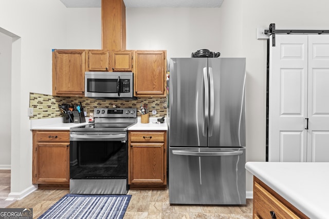 kitchen featuring appliances with stainless steel finishes, a barn door, tasteful backsplash, and a textured ceiling