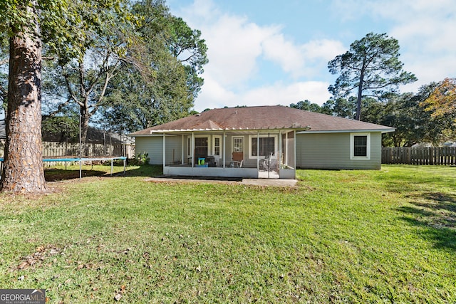 back of house with a sunroom, a trampoline, and a yard