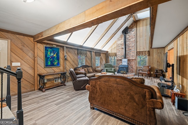 living room featuring light hardwood / wood-style floors, a wood stove, and wood walls