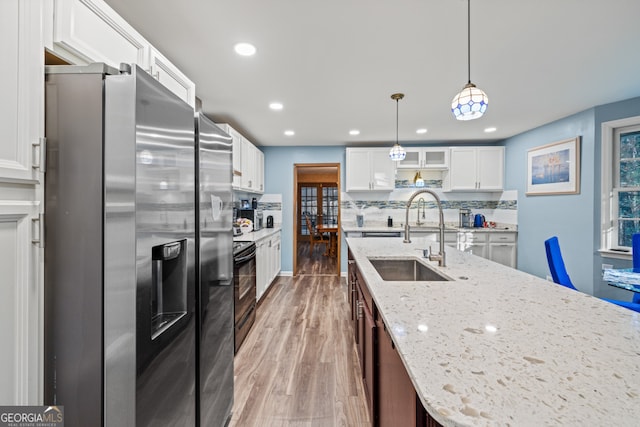 kitchen with sink, stainless steel refrigerator with ice dispenser, hardwood / wood-style floors, pendant lighting, and white cabinets