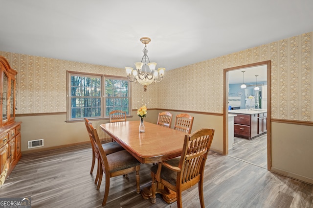 dining space with light wood-type flooring and a chandelier