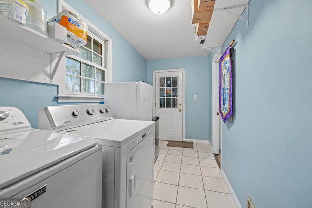 clothes washing area with washing machine and dryer and light tile patterned floors