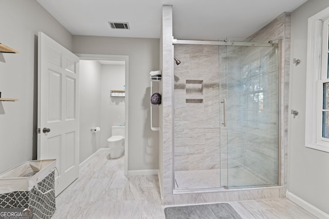 bathroom featuring a shower with shower door and toilet