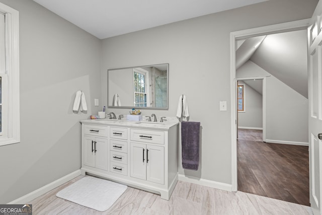 bathroom featuring vanity, wood-type flooring, and vaulted ceiling