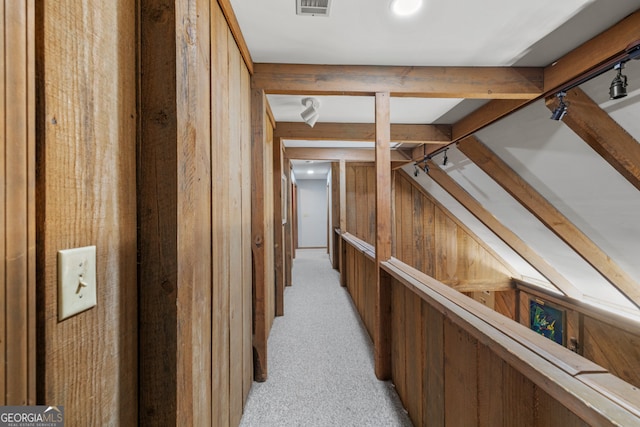 hall featuring light colored carpet and wooden walls