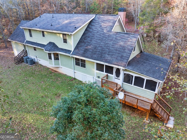 rear view of property featuring a sunroom, a deck, central air condition unit, and a yard