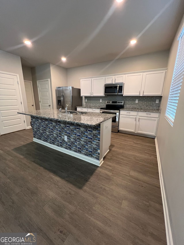 kitchen featuring a kitchen island with sink, appliances with stainless steel finishes, light stone counters, and backsplash