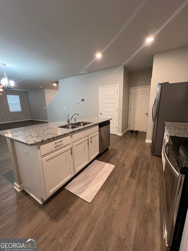 kitchen with light stone counters, stainless steel appliances, a sink, white cabinetry, and dark wood finished floors