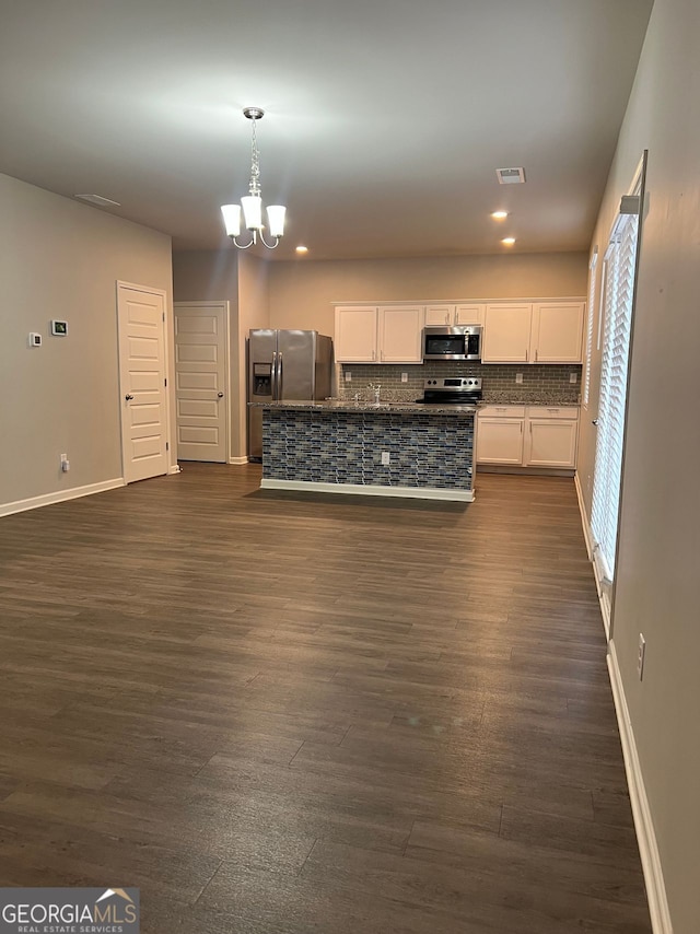 kitchen with a chandelier, appliances with stainless steel finishes, dark wood-style flooring, white cabinetry, and backsplash