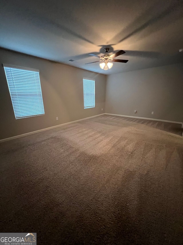 carpeted spare room with ceiling fan, visible vents, and baseboards