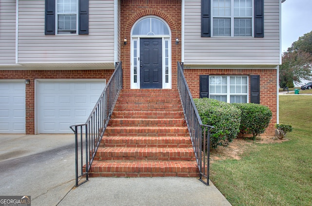 entrance to property featuring a lawn and a garage