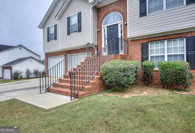 entrance to property featuring a lawn and a garage