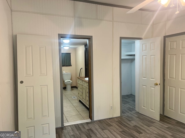 bedroom featuring dark hardwood / wood-style floors, ceiling fan, and connected bathroom