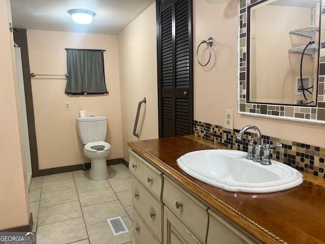 bathroom featuring tile patterned flooring, decorative backsplash, toilet, and vanity