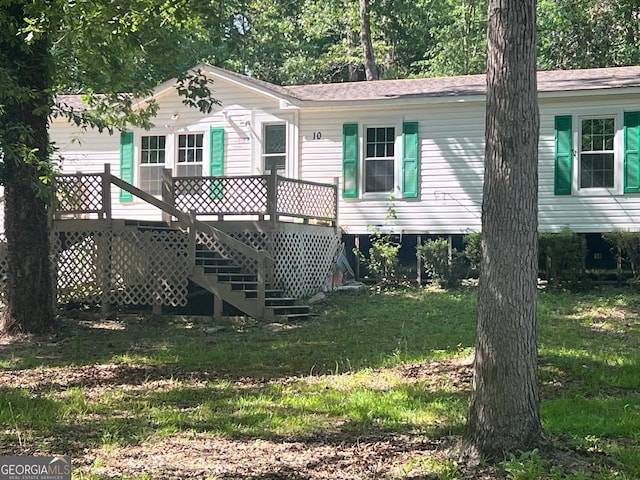 rear view of house with a lawn and a wooden deck