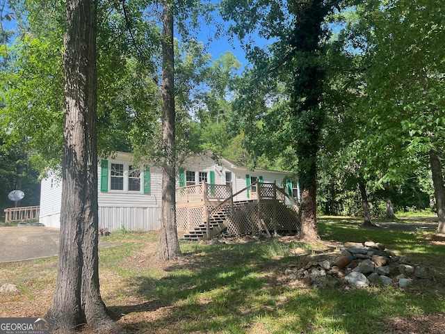 exterior space with a wooden deck and a front lawn