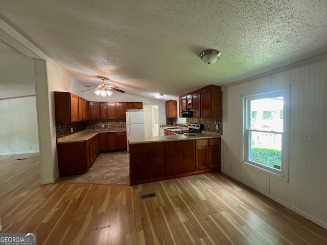 kitchen featuring backsplash, wooden walls, light wood-type flooring, white fridge, and kitchen peninsula