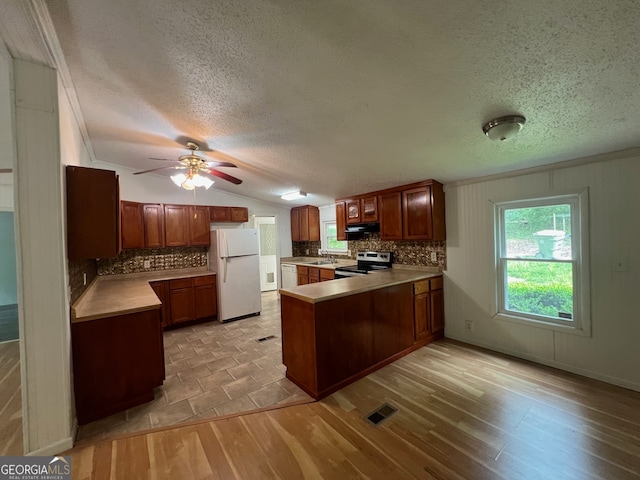 kitchen with white refrigerator, kitchen peninsula, a textured ceiling, electric stove, and light wood-type flooring