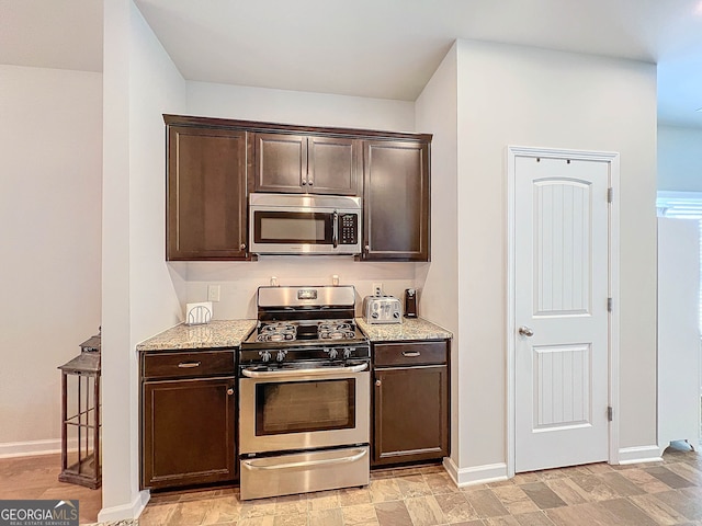 kitchen with dark brown cabinets, light stone counters, and appliances with stainless steel finishes