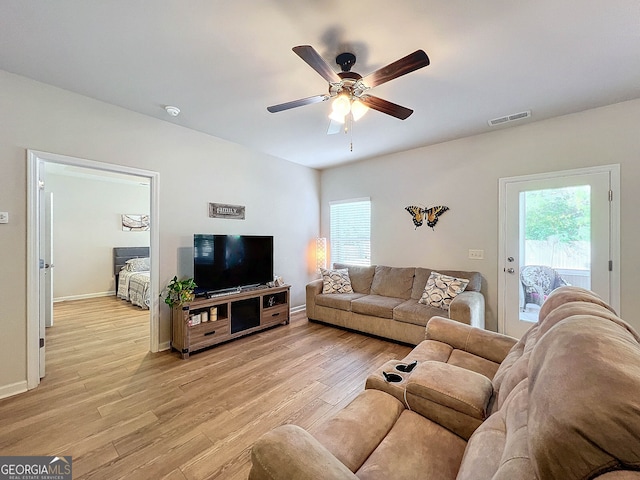 living room with a wealth of natural light, light hardwood / wood-style flooring, and ceiling fan