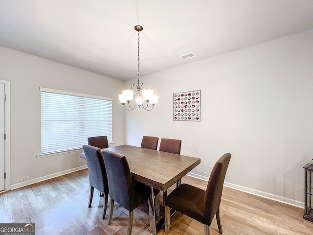 dining area featuring light hardwood / wood-style flooring and an inviting chandelier