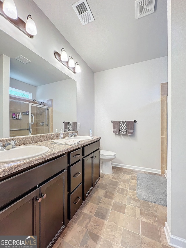 bathroom featuring vanity, toilet, and a shower with door