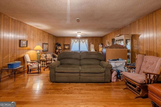 living room featuring wooden walls, light hardwood / wood-style floors, and a textured ceiling