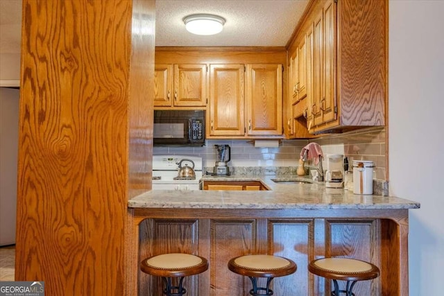 kitchen with white range oven, light stone counters, tasteful backsplash, and sink