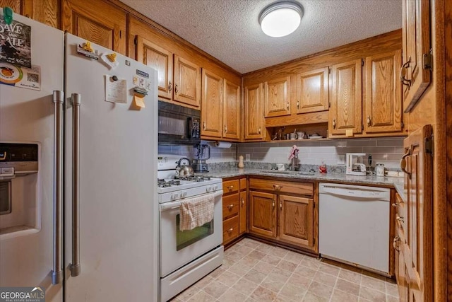 kitchen with a textured ceiling, white appliances, tasteful backsplash, and sink