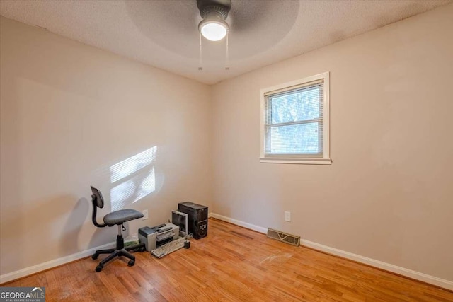 unfurnished office featuring a textured ceiling, hardwood / wood-style flooring, and ceiling fan