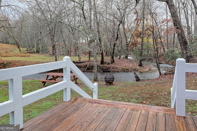 wooden terrace featuring a yard and an outdoor fire pit