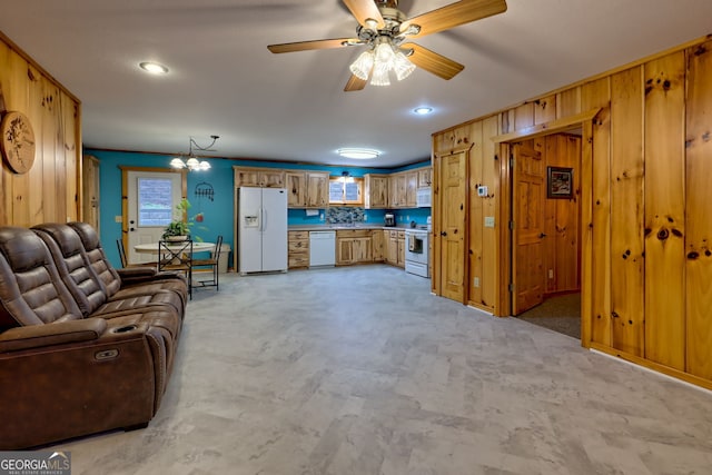 carpeted living room with ceiling fan with notable chandelier and wood walls