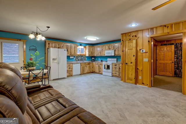 kitchen featuring white appliances, ceiling fan with notable chandelier, hanging light fixtures, wooden walls, and light colored carpet