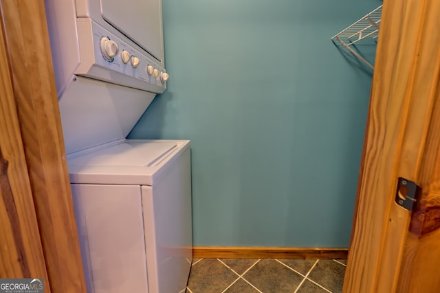 laundry room with stacked washer and dryer and dark tile patterned flooring