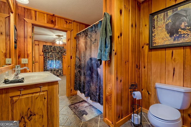 bathroom with ceiling fan, tile patterned flooring, toilet, wooden walls, and vanity